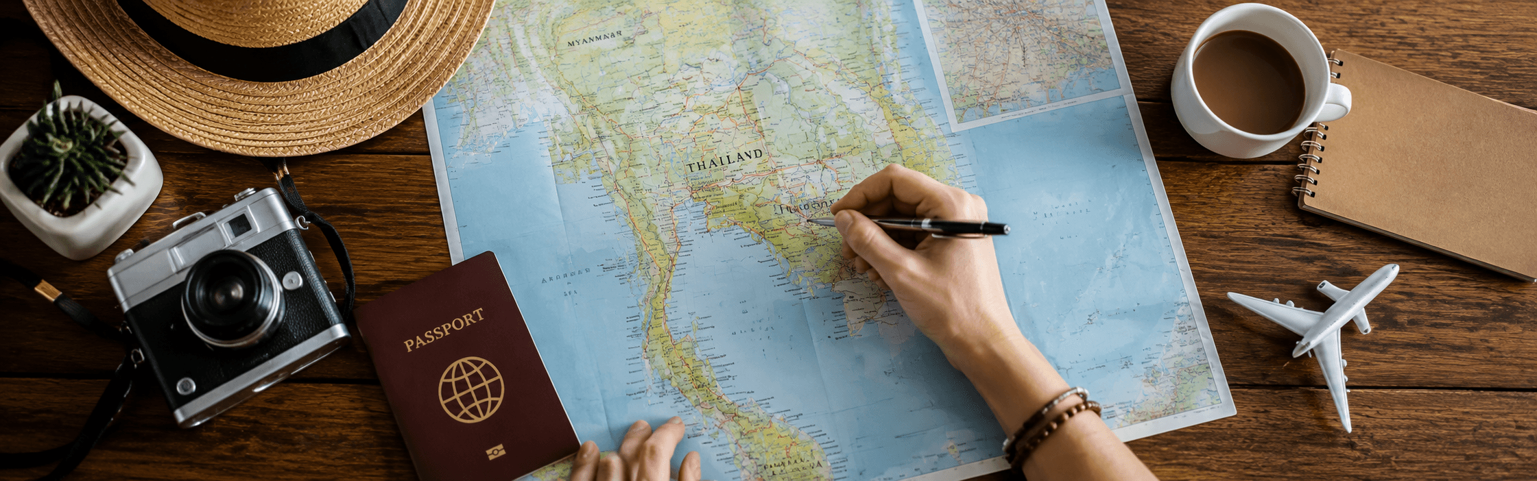 Aerial view of Thailand’s tropical islands with turquoise lagoons, lush green limestone cliffs, white-sand beaches, deep blue sea, and boats leaving wakes beneath a bright blue sky.